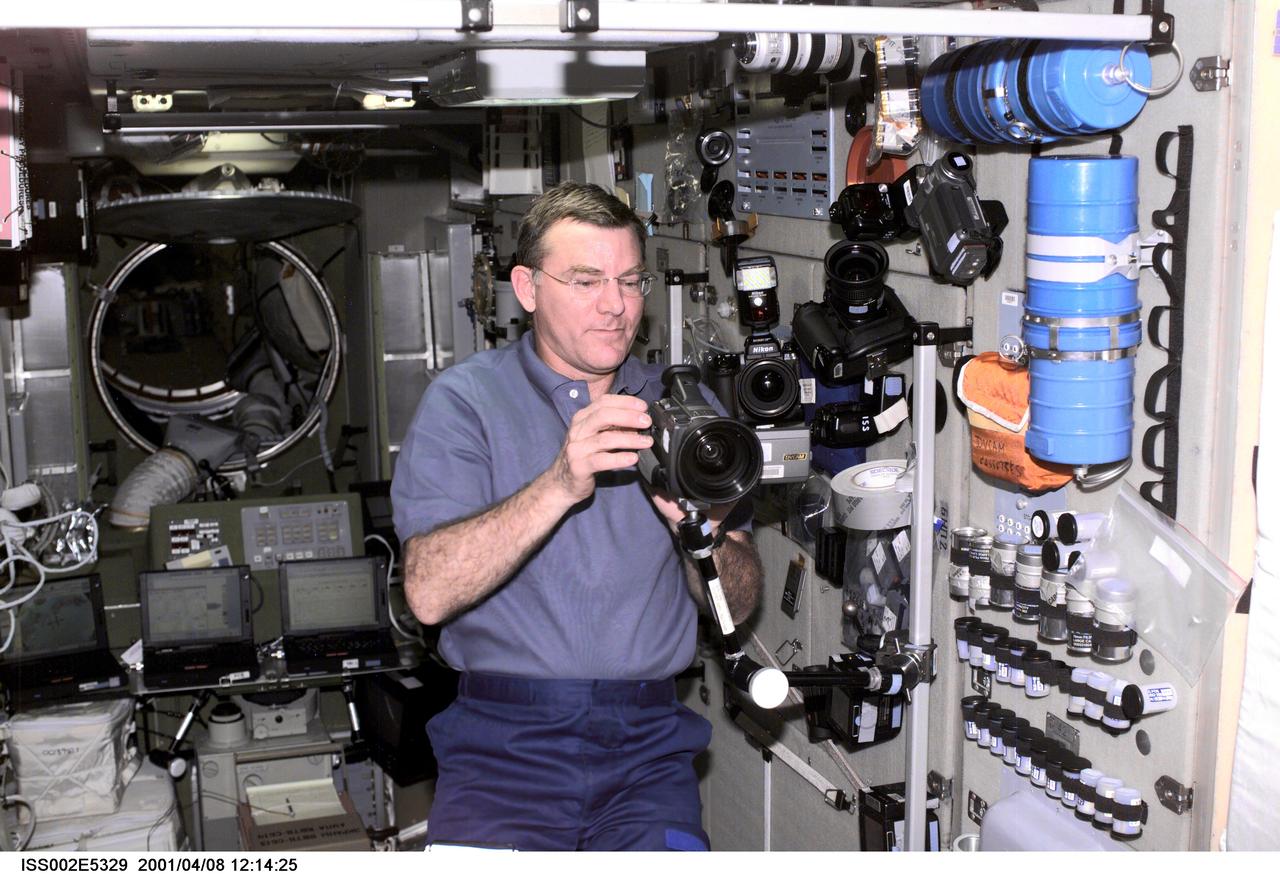 ISS002-E-5329 (08 April 2001) --- Astronaut James S. Voss, Expedition Two flight engineer, sets up a video camera on a mounting bracket in the Zvezda / Service Module of the International Space Station (ISS).  A 35mm camera and a digital still camera are also visible nearby.  This image was recorded with a digital still camera.
