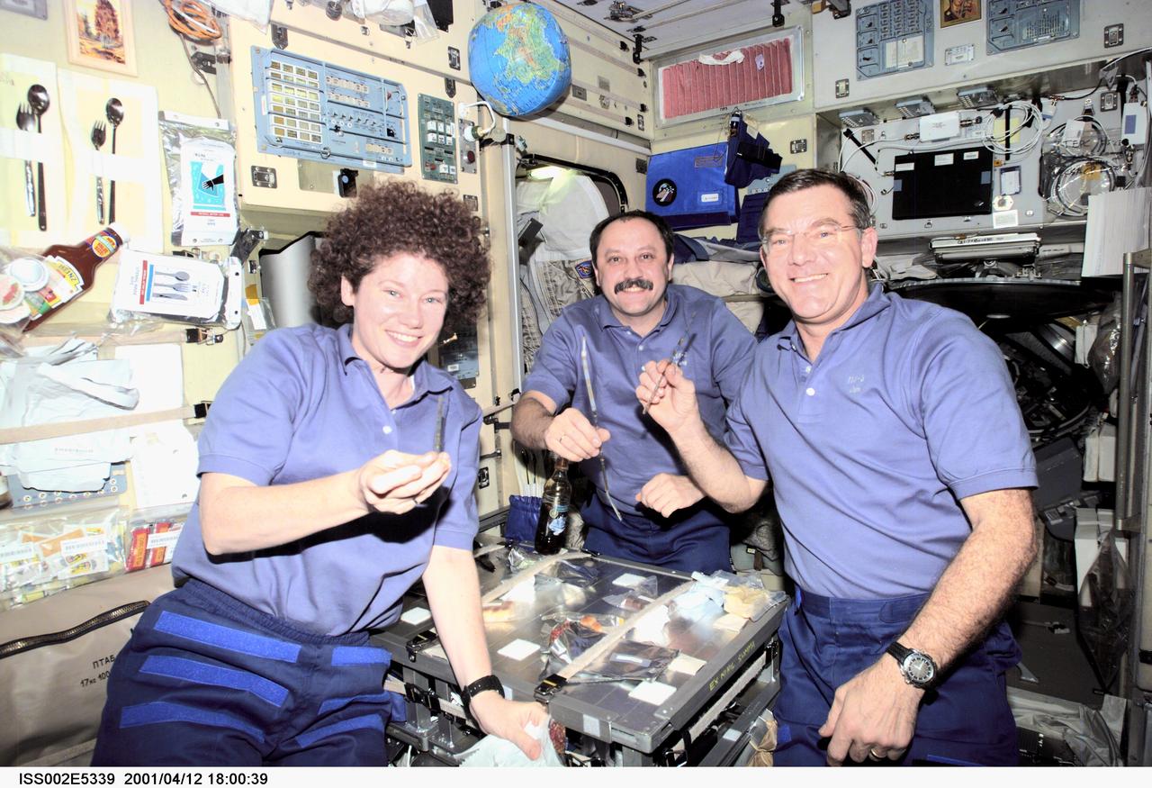 ISS002-E-5339 (12 April 2001) --- The Expedition Two crewmembers -- astronaut Susan J. Helms (left), cosmonaut Yury V. Usachev and astronaut James S. Voss -- share a meal at the table in the Zvezda / Service Module of the International Space Station (ISS).  This image was recorded with a digital still camera.