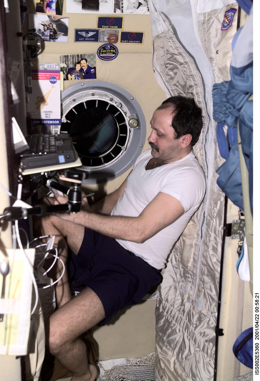 ISS002-E-5360 (22 April 2001) --- Cosmonaut Yury V. Usachev, Expedition Two mission commander, writes down some notes in his sleeping compartment in the Zvezda / Service Module of the International Space Station (ISS).  This image was recorded with a digital still camera.