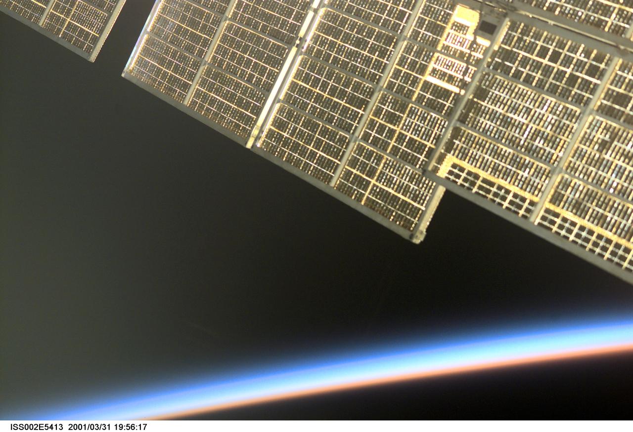 ISS002-E-5413 (31 March 2001) --- As the sun sets on the Earth's horizon, a golden reflection emanates from the solar array of the Zvezda / Service Module of the International Space Station (ISS).  An Expedition Two crewmember took this unusual photograph with a digital still camera.
