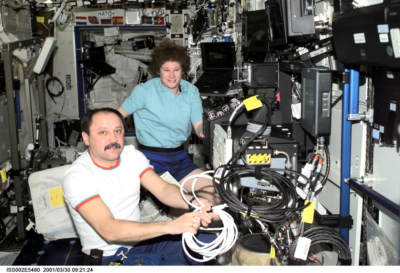 ISS002E5480 (30 March 2001) --- Cosmonaut Yury V. Usachev (foreground), Expedition Two mission commander, and astronaut Susan J. Helms, Expedition Two flight engineer, install cables for the Space Station Remote Manipulator System (SSRMS) or Canadarm2 control panel in preparation for the delivery of the Canadarm2 by the STS-100 crew in April. This image was recorded with a digital still camera.