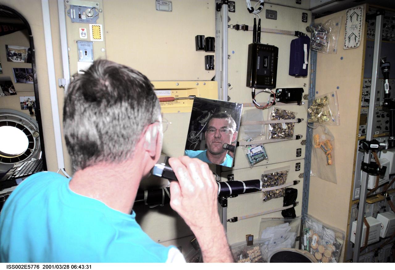 ISS002-E-5776 (28 March 2001) --- James S. Voss, Expedition Two flight engineer, shaves with an electric razor in the Zvezda Service Module.  The image was taken with a digital still camera.