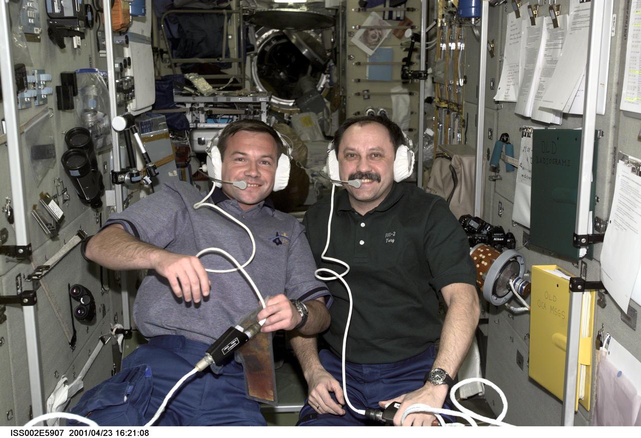 ISS002-E-5907 (23 April 2001) --- Two cosmonauts representing Rosaviakosmos, Yuri V. Lonchakov (left), STS-100 mission specialist, and Yury V. Usachev, Expedtion Two mission commander, communicate with mission control using headsets in the Zvezda Service Module during the STS-100 visit to the International Space Station (ISS). The image was taken with a digital still camera.