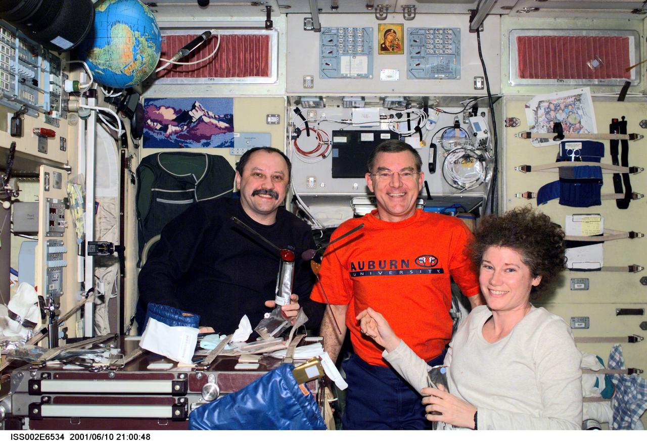 ISS002-E-6534  (10 June 2001) --- Expedition Two crewmembers Yury V. Usachev (left), mission commander, James S. Voss, flight engineer, and Susan J. Helms, flight engineer, share a dessert in the Zvezda Service Module.  Usachev represents Rosaviakosmos.  The image was recorded with a digital still camera.