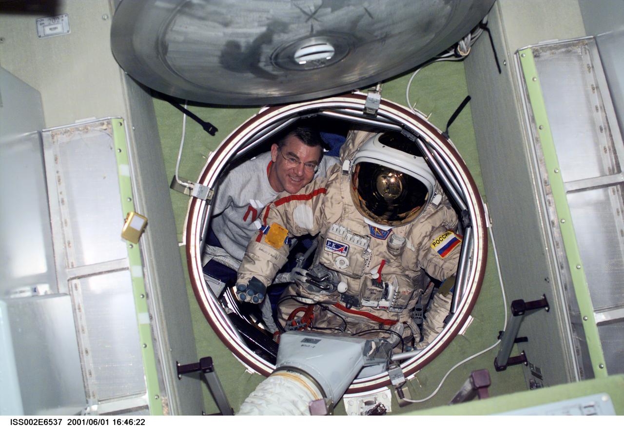 ISS002-E-6537 (1 June 2001) ---  Astronaut James S. Voss, Expedition Two flight engineer, moves an Orlan spacesuit through the forward hatch of the Zvezda Service Module.   The image was recorded with a digital still camera.
