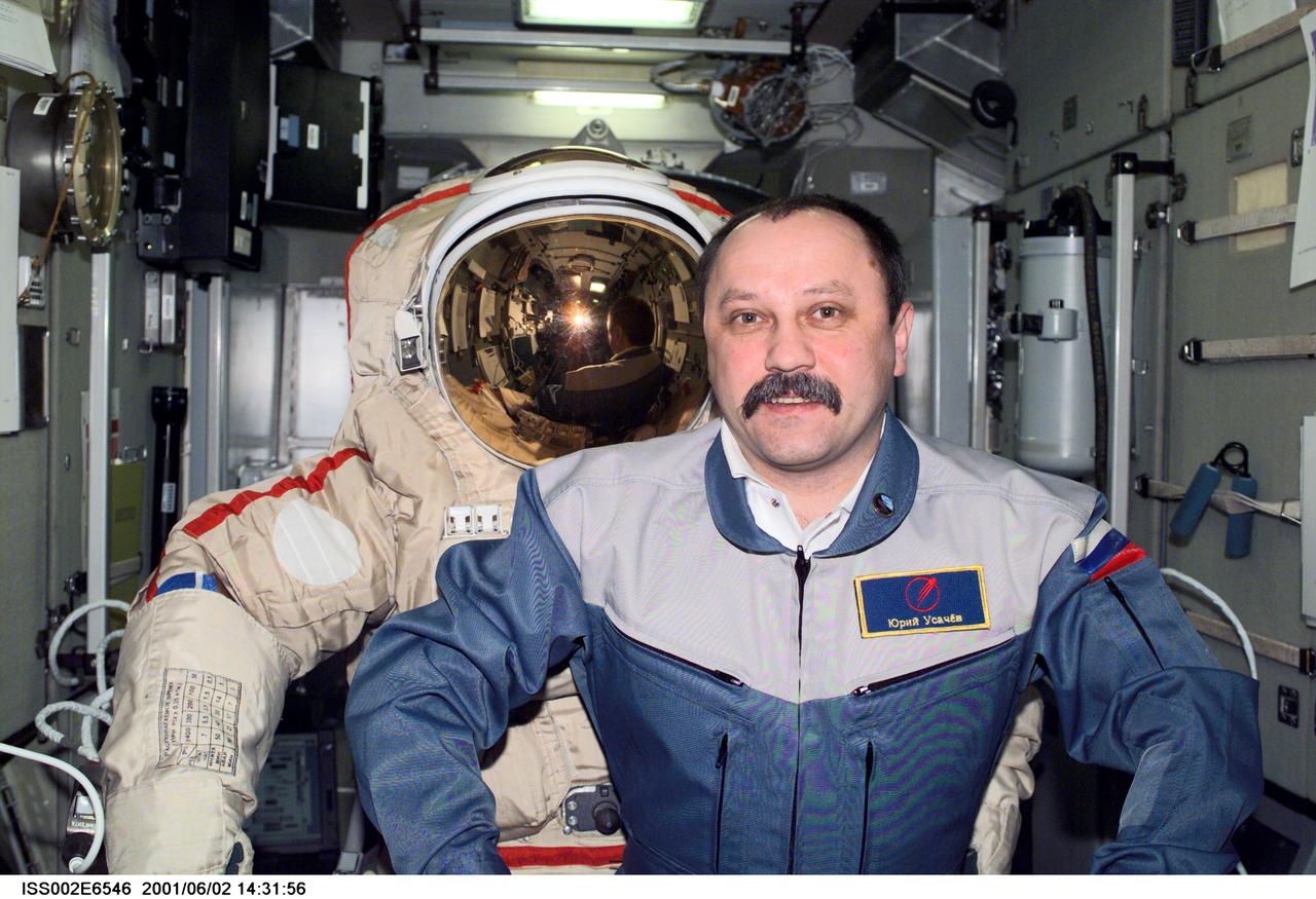 ISS002-E-6546 (1 June 2001) ---  Cosmonaut Yury V. Usachev of Rosaviakosmos, Expedition Two mission commander, mimics the natural stance of an empty Orlan spacesuit in the Zvezda Service Module.  This image was taken with a digital still camera.