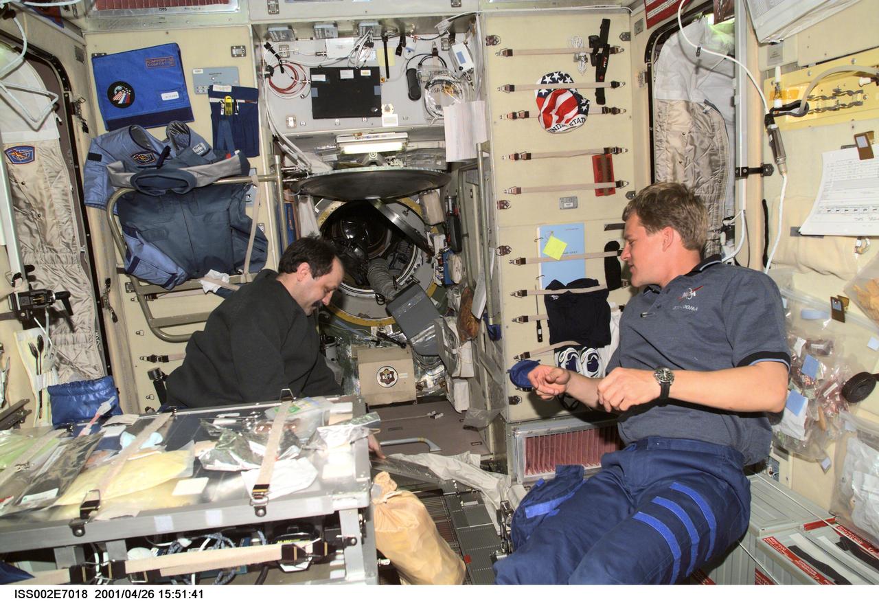 ISS002-E-7018 (26 April 2001) --- Astronaut Scott E. Parazynski, STS-100 mission specialist, talks with cosmonaut Yury V. Usachev, Expedition Two commander, who is conducting maintenance on the Treadmill Vibration Isolation System (TVIS) in the Zvezda/Service Module. A digital still camera was used to record this image.
