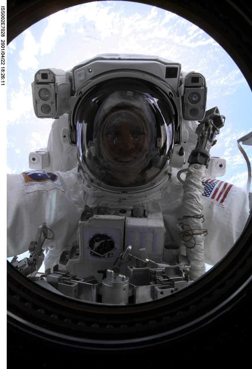 ISS002-E-7028 (22 April 2001) --- Astronaut Scott E. Parazynski, STS-100 mission specialist, peers into the Destiny/U.S. Laboratory's nadir window during the first space walk (EVA-1) of the STS-100 mission. A digital still camera was used to record this image.