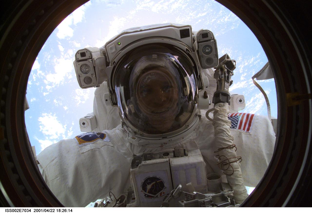 ISS002-E-7034 (22 April 2001) --- Astronaut Scott E. Parazynski, STS-100 mission specialist, peers into the Destiny Laboratory's nadir window during the first extravehicular activity of the STS-100 mission. This image was recorded with a digital still camera by an Expedition Two crew member.