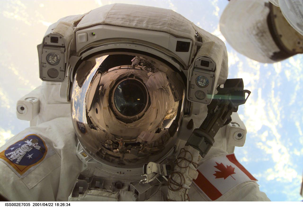 ISS002-E-7035 (22 April 2001) --- A through-the-window  view of  astronaut Chris A. Hadfield, STS-100 mission specialist representing the Canadian Space Agency (CSA), was taken during the first extravehicular activity (EVA) of the STS-100 mission.  This digital still camera's image was captured by the Expedition Two crew through the nadir window of the Destiny Laboratory with a digital still camera.  The window and much of Destiny can be seen in the visor of Hadfield's helmet.