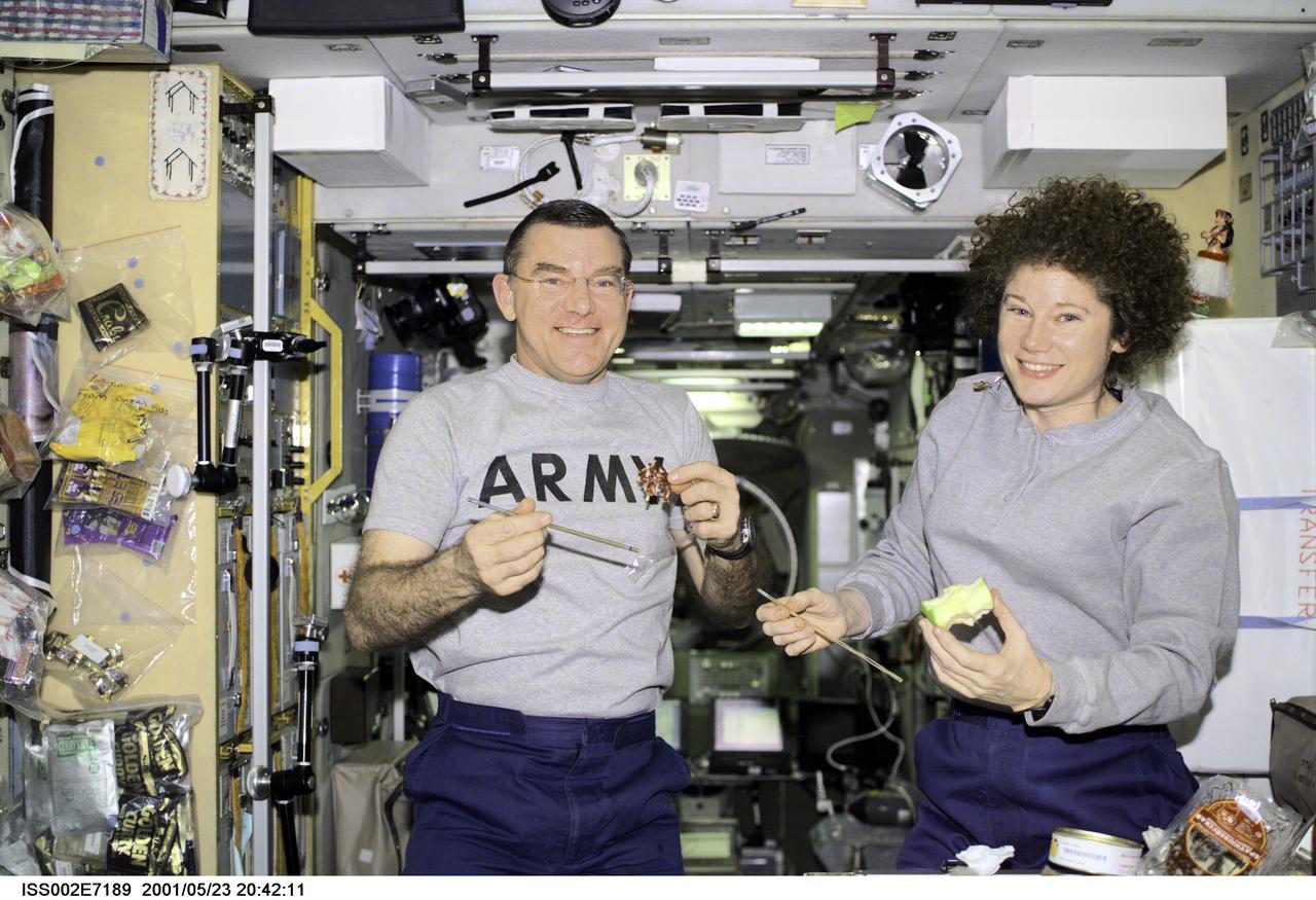 ISS002-E-7189 (23 May 2001) --- Astronauts James S. Voss and Susan J. Helms take a snack break in the Zvezda Service Module. The Expedition Two flight engineers were captured with a digital still camera by Rosaviakosmos cosmonaut Yury V. Usachev, commander.