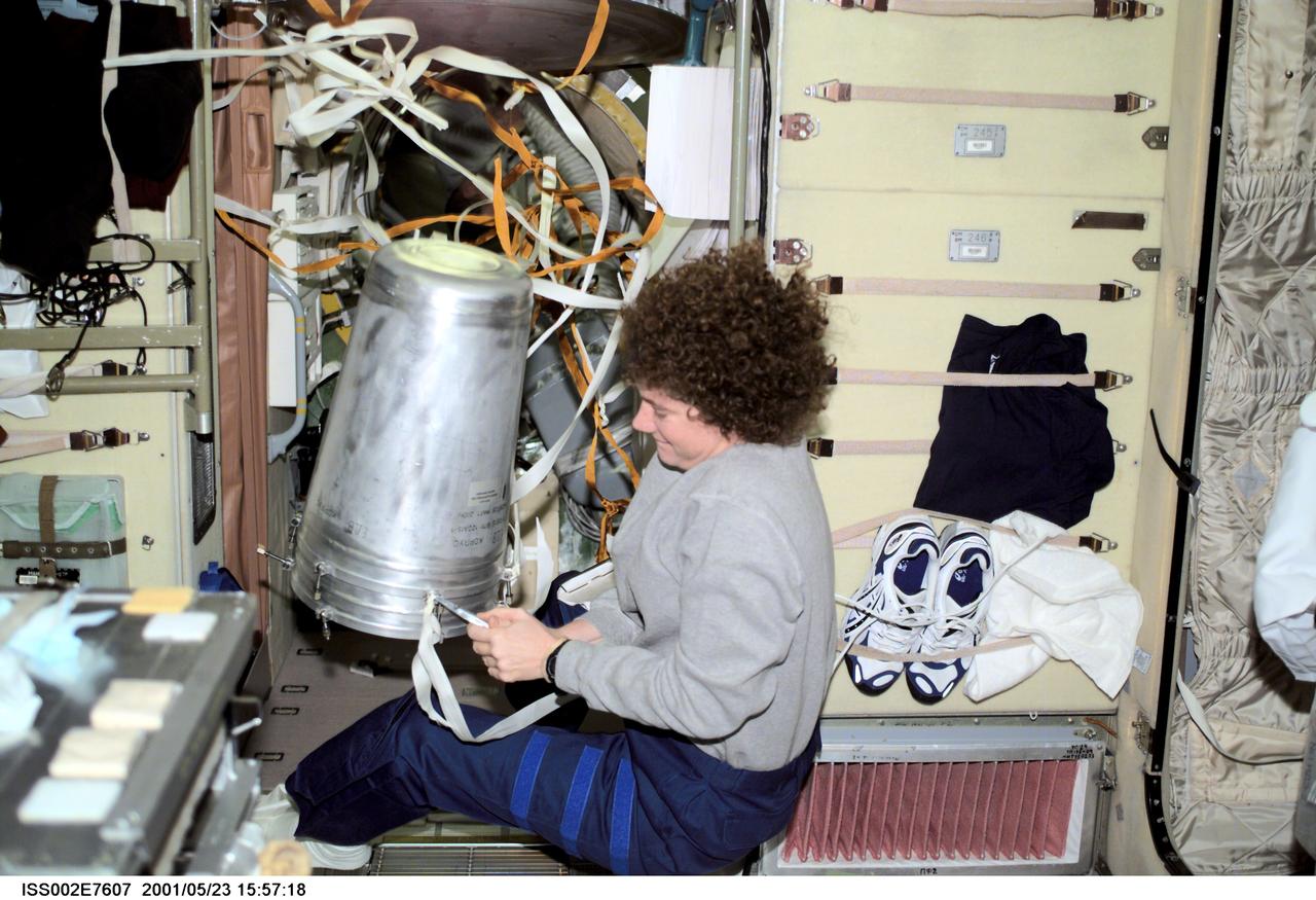 ISS002-E-7607 (23 May 2001) --- Susan J. Helms, Expedition Two flight engineer, works with a strap on a water container in the Zvezda Service Module.  The image was taken with a digital still camera.