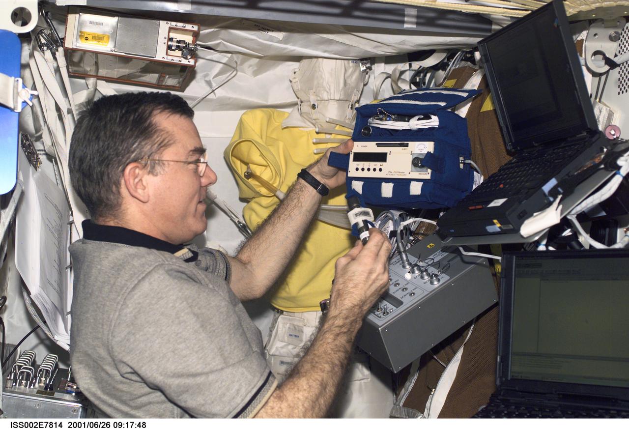ISS002-E-7814 (26 June 2001) --- James S. Voss, Expedition Two flight engineer, sets up the Human Research Facility's (HRF) Dosimetric Mapping (DOSMAP) Power Distribution Unit (PDU) in Destiny. The image was taken with a digital still camera.