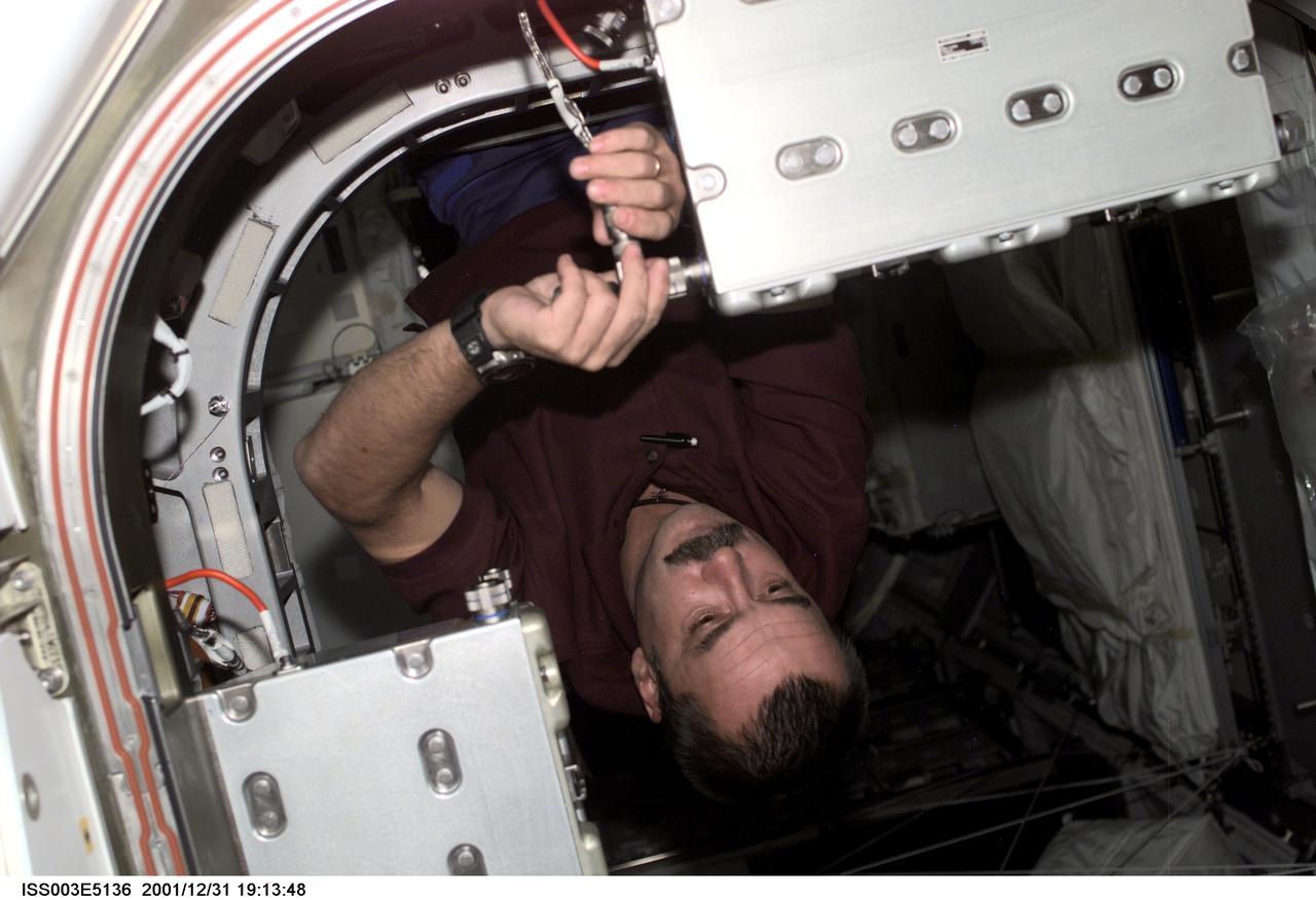 ISS003-E-5136 (August 2001) --- Mikhail Tyurin of Rosaviakosmos, Expedition Three flight engineer, secures a connection on a Controller Power Assembly (CPA) in a hatchway on Unity Node 1.  This image was taken with a digital still camera.