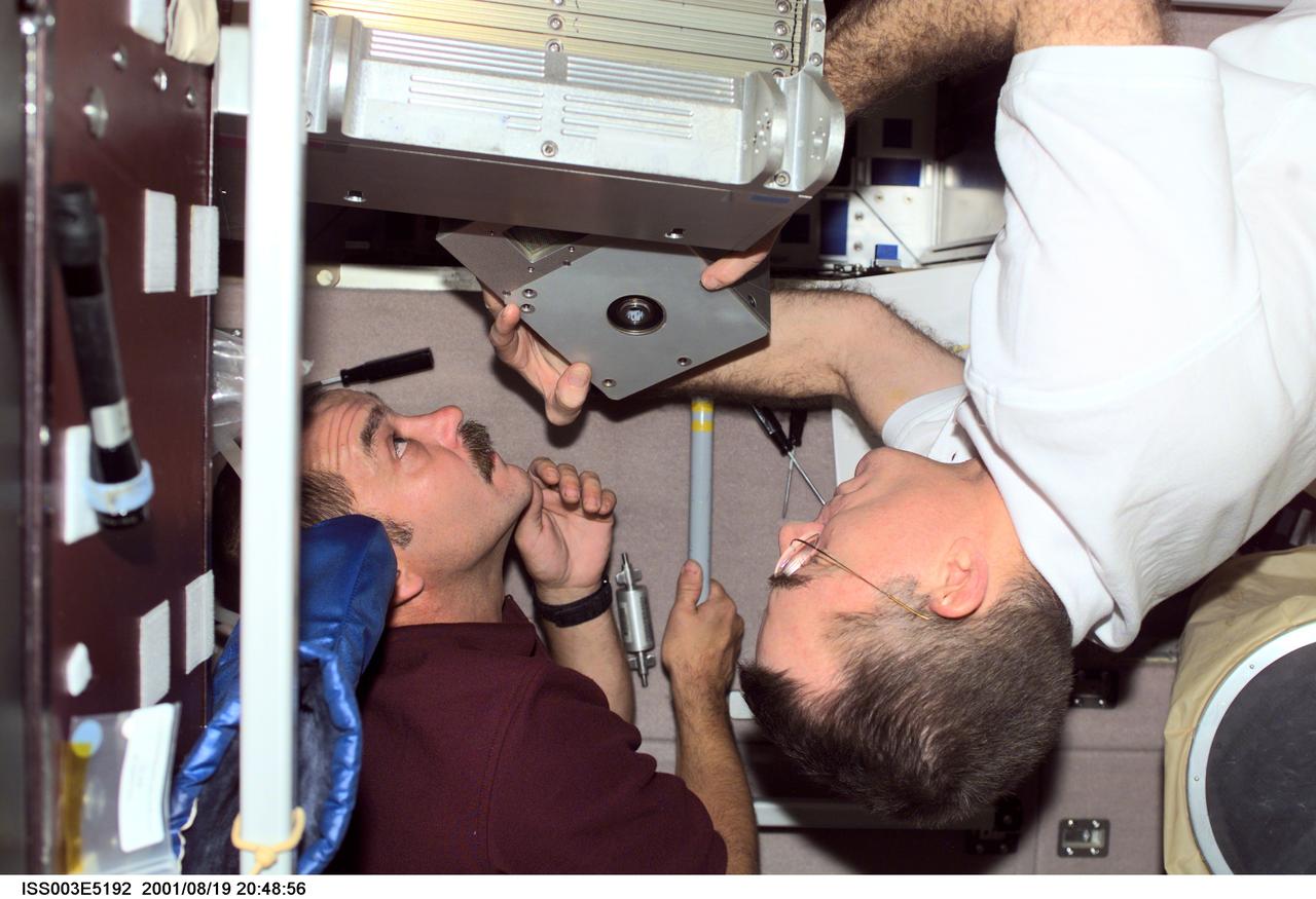 ISS003-E-5192 (19 August 2001) --- Cosmonaut Mikhail Tyurin (left), Expedition Three flight engineer representing Rosaviakosmos, and astronaut James S. Voss, Expedition Two flight engineer, perform maintenance in the Zvezda Service Module on the International Space Station (ISS). This image was taken with a digital still camera.