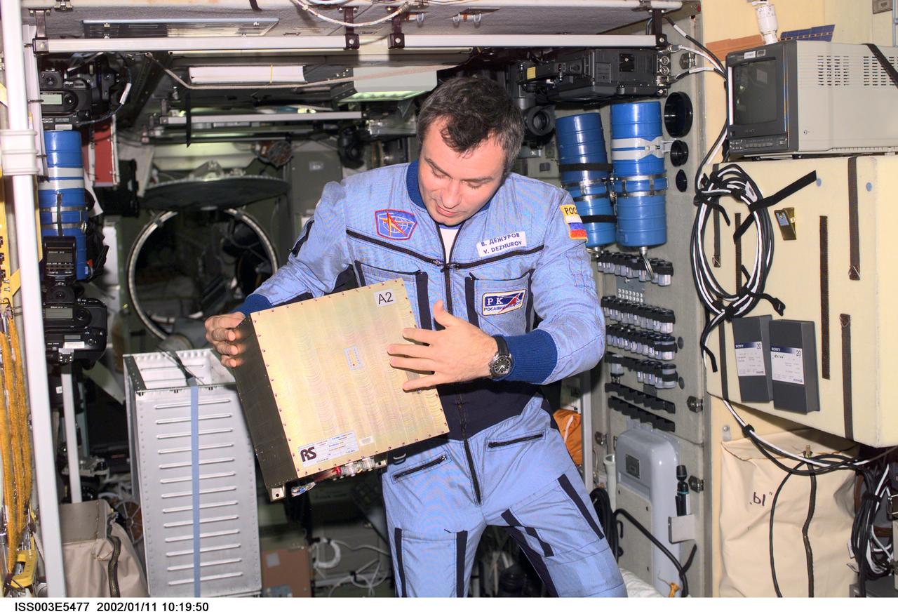 ISS003-E-5477 (August 2001) --- Cosmonaut Vladimir Dezhurov of Rosaviakosmos, Expedition Three flight engineer, holds a Global Time System (GTS) electronics unit in the Zvezda Service Module. Please note: The date identifiers on some frames are not accurate due to a technical problem with one of the Expedition Three cameras. When a specific date is given in the text or description portion, it is correct.