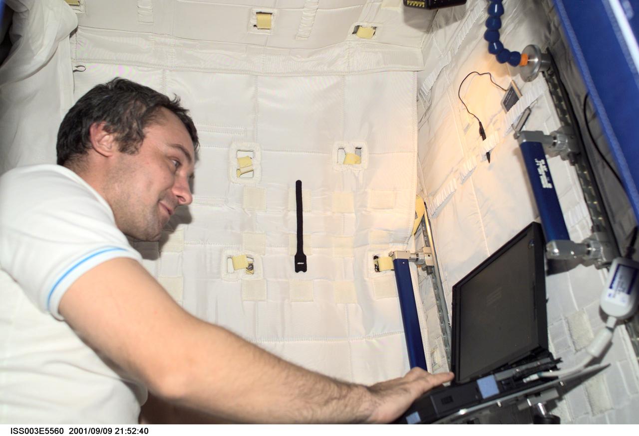 ISS003-E-5560 (9 September 2001) ---  Cosmonaut Vladimir Dezhurov of Rosaviakosmos, Expedition Three flight engineer, works on a laptop computer in the Temporary Sleep Station (TSS) in the U.S. Laboratory.