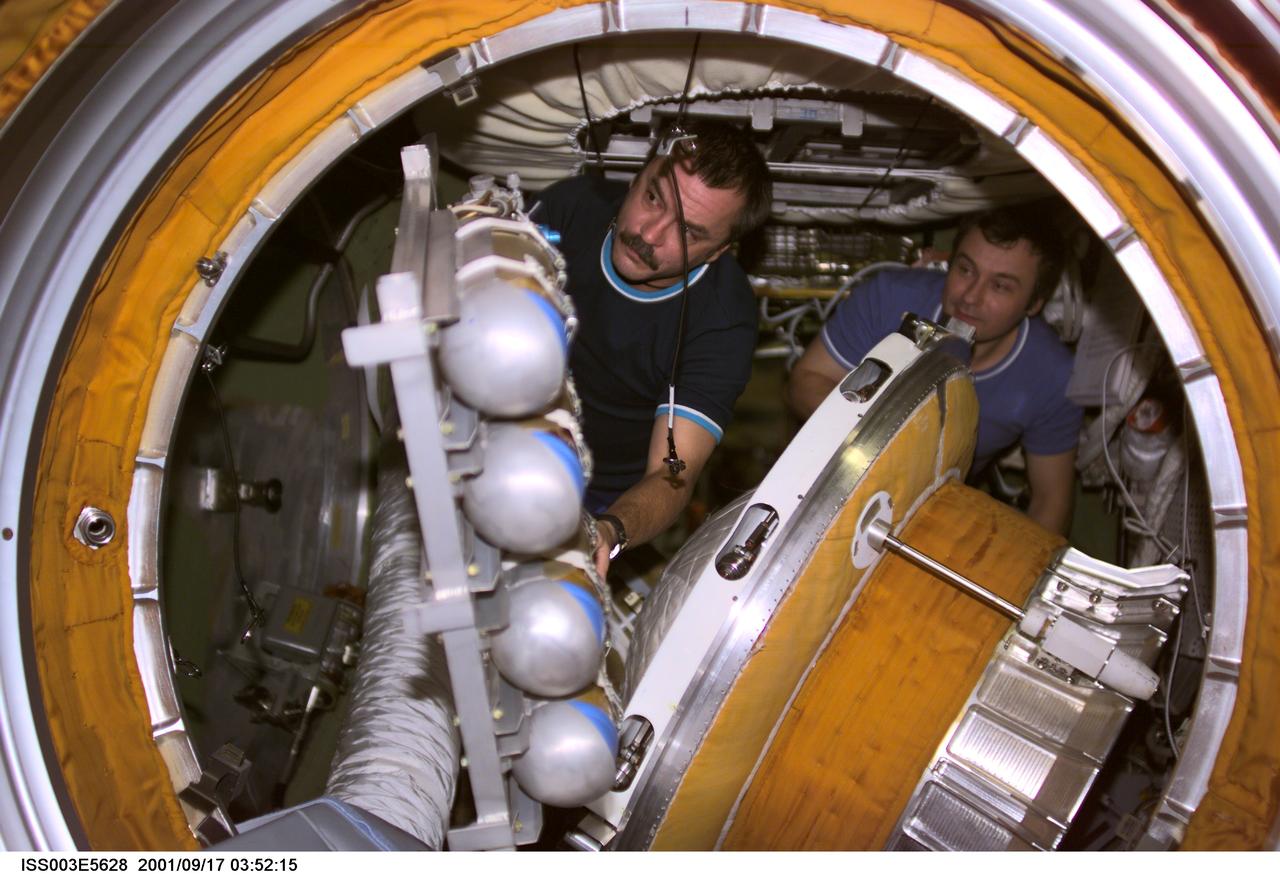 ISS003-E-5628 (17 September 2001) --- Cosmonaut Mikhail Tyurin (left) and cosmonaut Vladimir Dezhurov, Expedition Three flight engineers, remove the docking probe in the Zvezda Service Module's transfer compartment.  The docking probe successfully guided the arrival of the Russian built Pirs docking compartment to the International Space Station (ISS).  Tyurin and Dezhurov represent Rosaviakosmos.