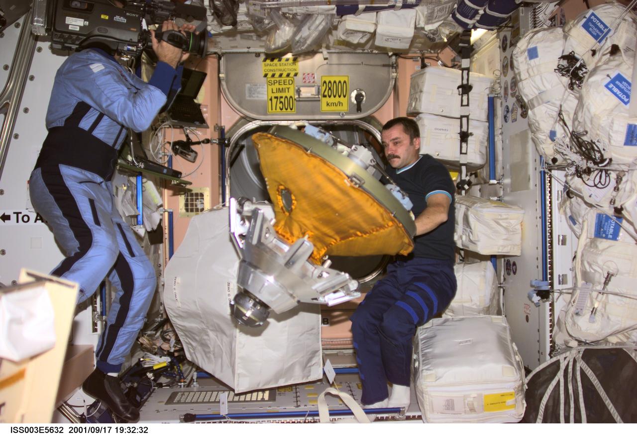 ISS003-E-5632 (17 September 2001) --- Cosmonaut Mikhail Tyurin, Expedition Three flight engineer, packs the docking probe in a stowage bag in Unity. Cosmonaut Vladimir Dezhurov, flight engineer, videotapes the event. The docking probe successfully guided the arrival of the Russian-built Pirs docking compartment to the International Space Station (ISS). Tyurin and Dezhurov represent Rosaviakosmos.
