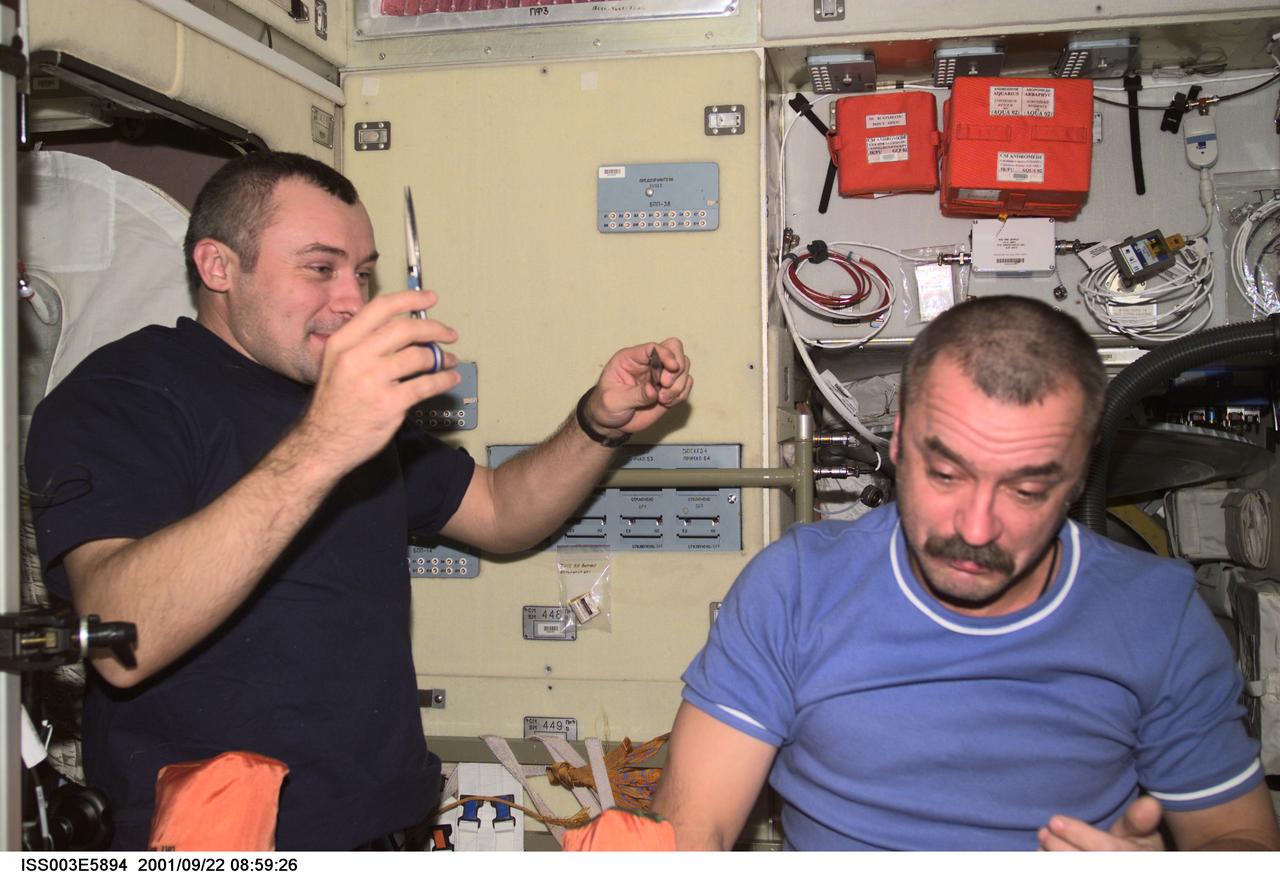ISS003-E-5894 (22 September 2001) --- Cosmonauts Vladimir N. Dezhurov (left) and Mikhail Tyurin, Expedition Three flight engineers representing Rosaviakosmos, take turns cutting hair in the Zvezda Service Module on the International Space Station (ISS). This image was taken with a digital still camera.