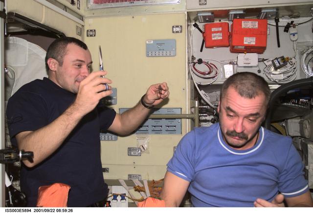 NASA image: Dezhurov gives Tyurin a haircut in the Service Module during Expedition Three