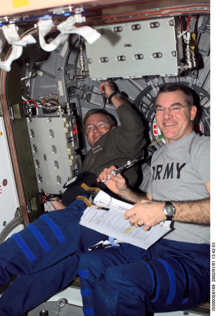 ISS003-E-6168 (August 2001) --- Astronauts Frank L. Culbertson, Jr., Expedition Three mission commander, and James S. Voss, Expedition Two flight engineer, perform routine tasks in the Unity node on the International Space Station (ISS). This image was taken with a digital still camera.