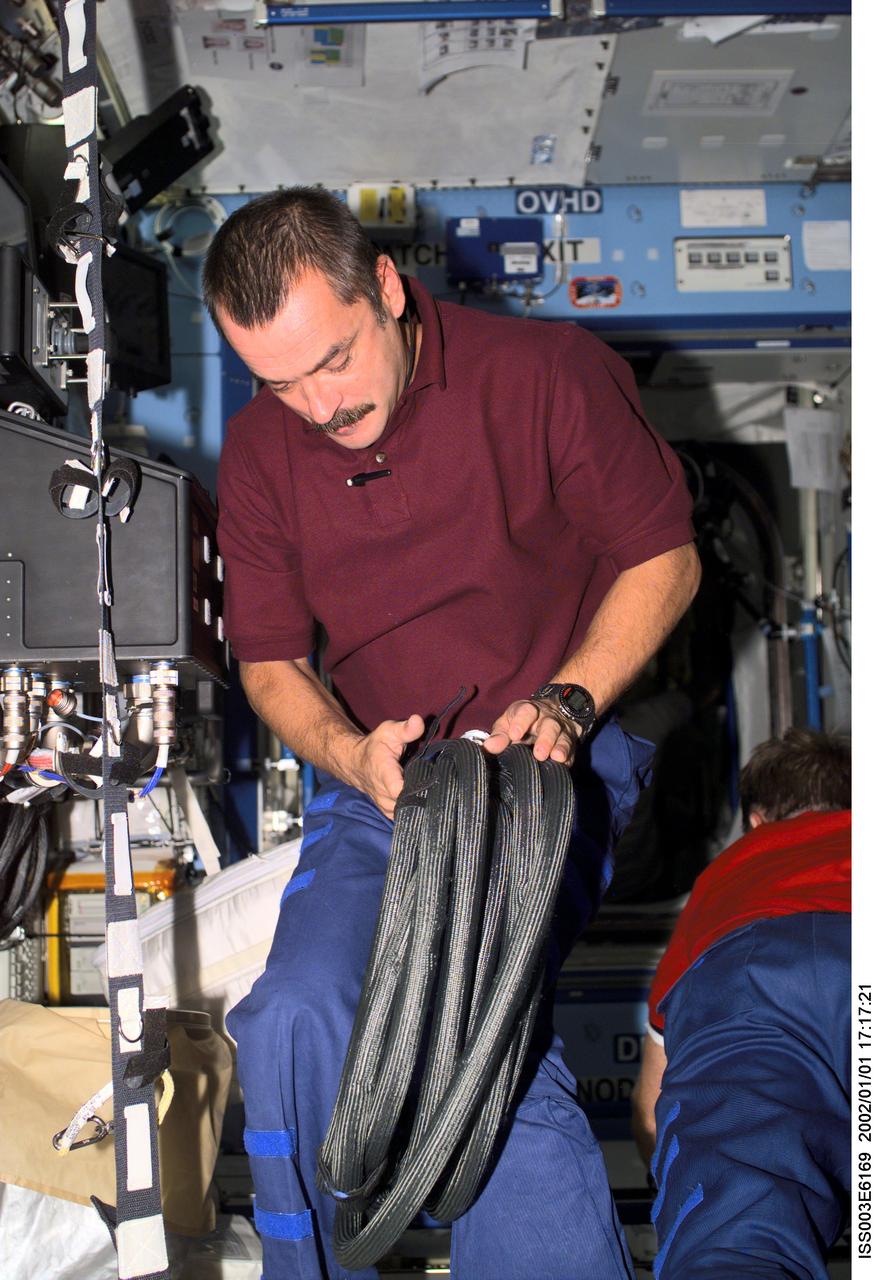 ISS003-E-6169 (August 2001) --- Cosmonaut Mikhail Tyurin, Expedition Three flight engineer representing Rosaviakosmos, works with cables in the Destiny laboratory on the International Space Station (ISS). This image was taken with a digital still camera.