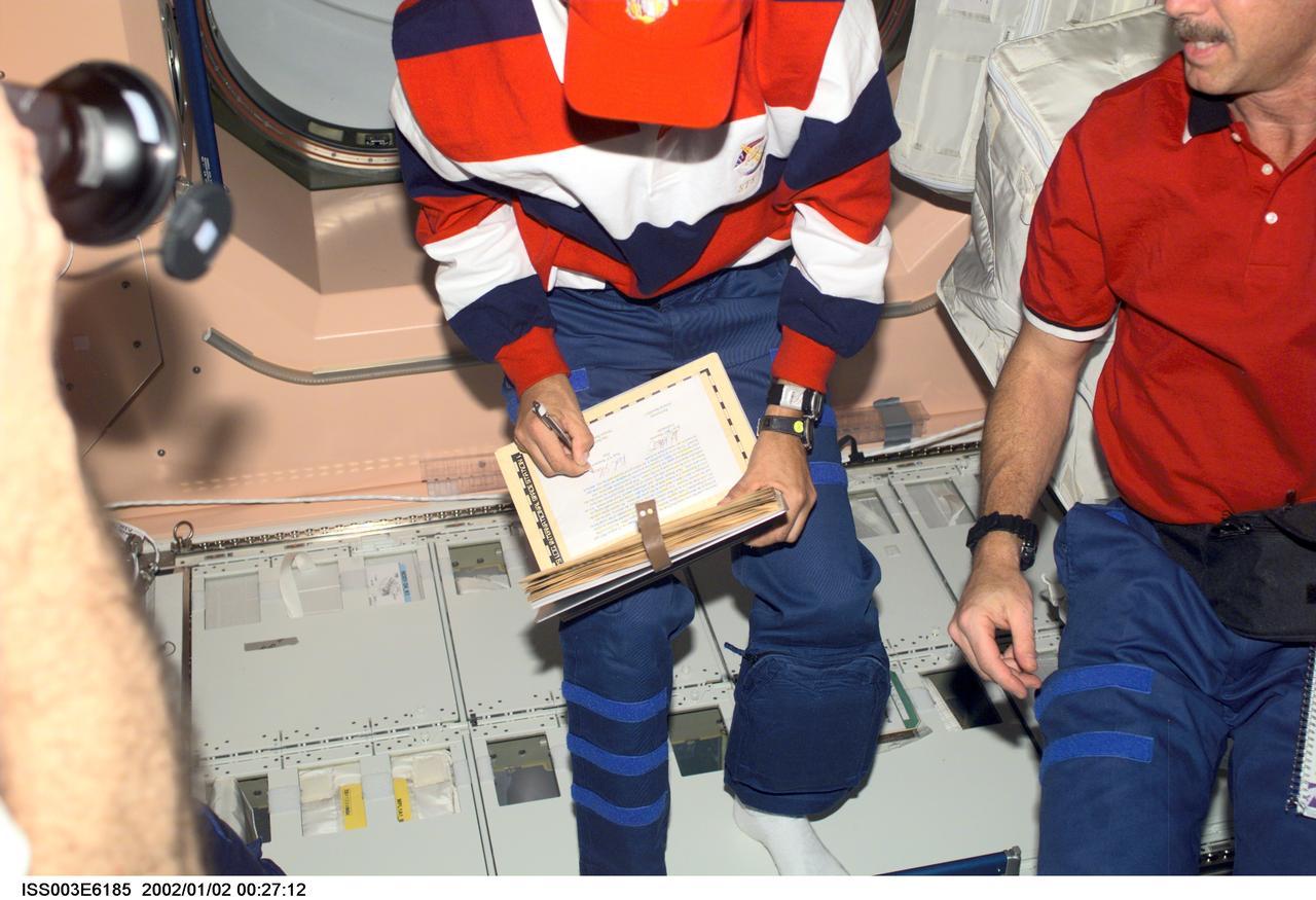 ISS003-E-6185 (August 2001) --- Astronauts Frederick W. (Rick) Sturckow (left), STS-105 pilot, and Scott J. Horowitz, mission commander, add their names to the ship&#0146;s log of visitors in the Unity node on the International Space Station (ISS). This image was taken with a digital still camera.