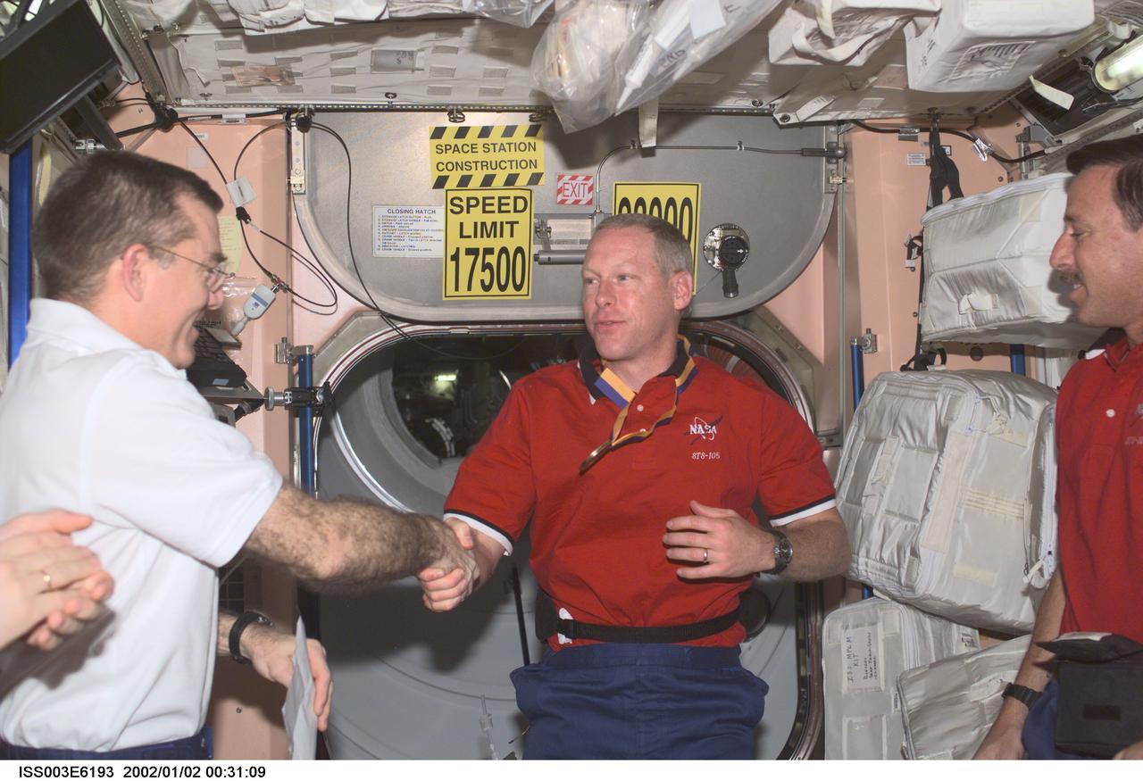 ISS003-E-6193 (August 2001) --- Astronauts James S. Voss (left), Expedition Two flight engineer, Patrick G. Forrester, STS-105 mission specialist, and Scott J. Horowitz, mission commander, exchange greetings in the Unity node on the International Space Station (ISS). This image was taken with a digital still camera.