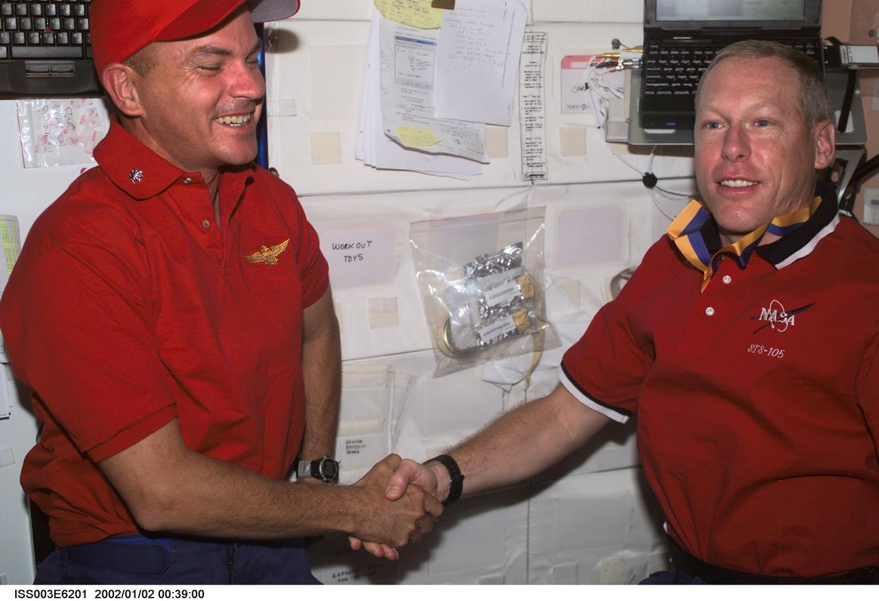 ISS003-E-6201 (August 2001) --- Astronauts Frederick W. (Rick) Sturckow (left), STS-105 pilot, and Patrick G. Forrester, mission specialist, exchange handshakes aboard the Unity node on the International Space Station (ISS). This image was taken with a digital still camera.