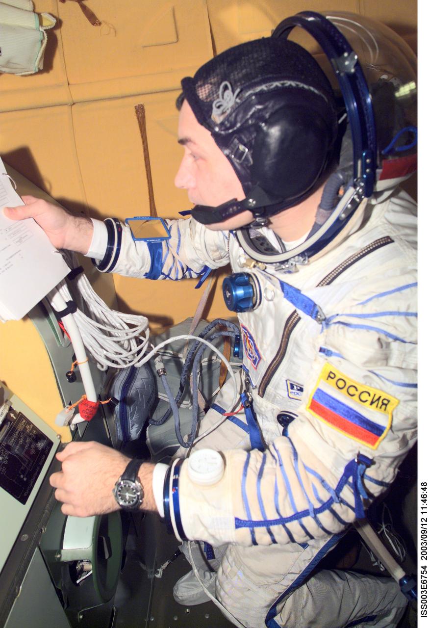 ISS003-E-6754 (October 2001) --- Cosmonaut Vladimir N. Dezhurov, Expedition Three flight engineer, wearing a Russian Sokol suit, checks a procedures checklist in the Soyuz spacecraft that is docked to the International Space Station (ISS). This Soyuz return vehicle will be moved from the Earth-facing port of the Zarya module for the linkup to the new Pirs Docking Compartment. The move of the Soyuz will mark the first time the new Pirs, which arrived at the station September 17, 2001, will serve as a docking port. The Soyuz will be shifted to prepare for the arrival of a new Soyuz return craft, to be launched October 21, 2001 from the Baikonur Cosmodrome in Kazakhstan. The Soyuz can serve as a crew return vehicle at the station for a maximum of about six months. Dezhurov represents Rosaviakosmos. This image was taken with a digital still camera.