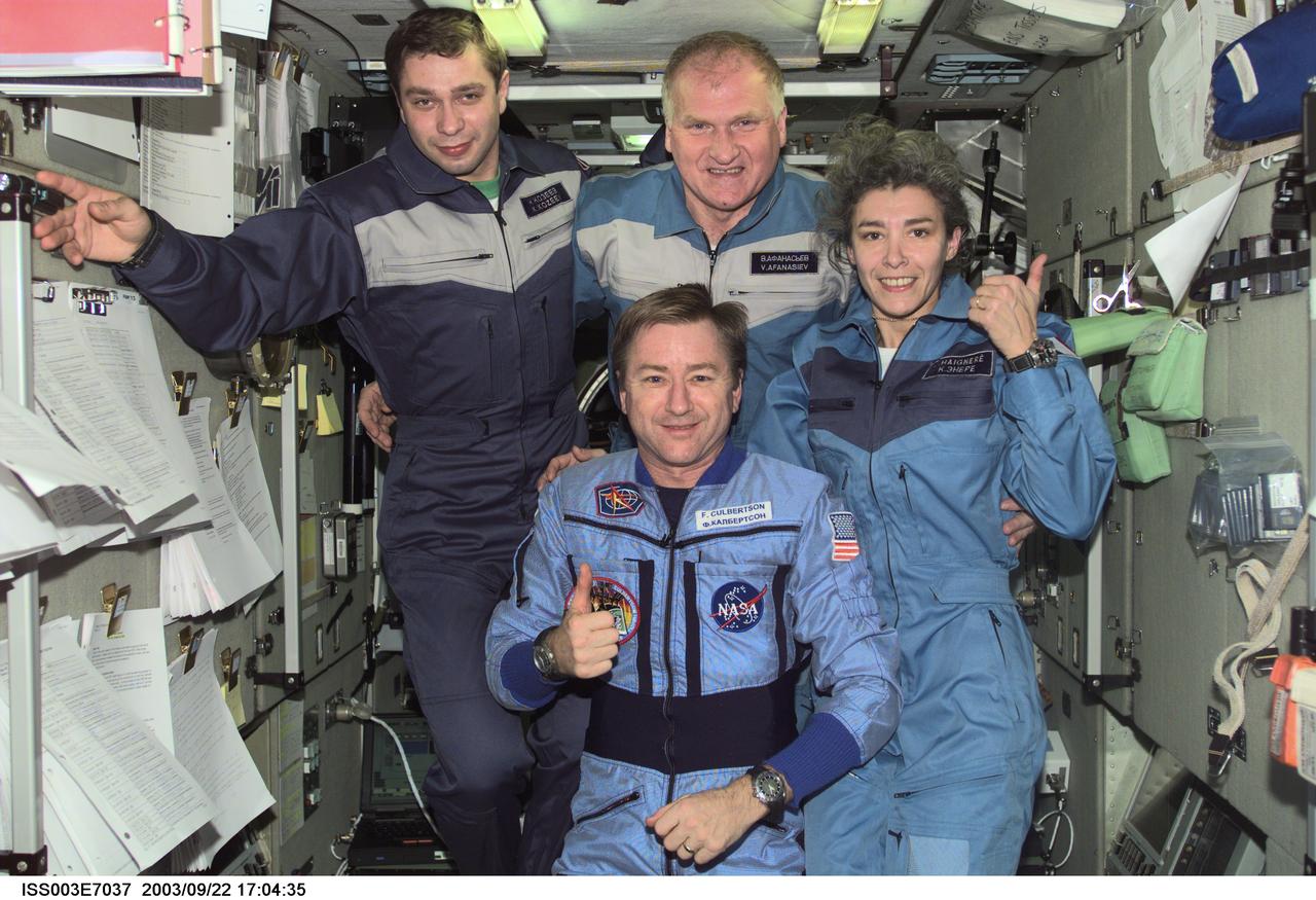 ISS003-E-7037 (23-31 October 2001) --- Astronaut Frank L. Culbertson, Jr. (foreground), Expedition Three mission commander, and the Soyuz Taxi crewmembers assemble for a group photo in the Zvezda Service Module on the International Space Station (ISS). From the left are Flight Engineer Konstantin Kozeev, Commander Victor Afanasyev, and French Flight Engineer Claudie Haignere. Afanasyev and Kozeev represent Rosaviakosmos, and Haignere represents ESA, carrying out a flight program for CNES, the French Space Agency, under a commercial contract with the Russian Aviation and Space Agency. This image was taken with a digital still camera.