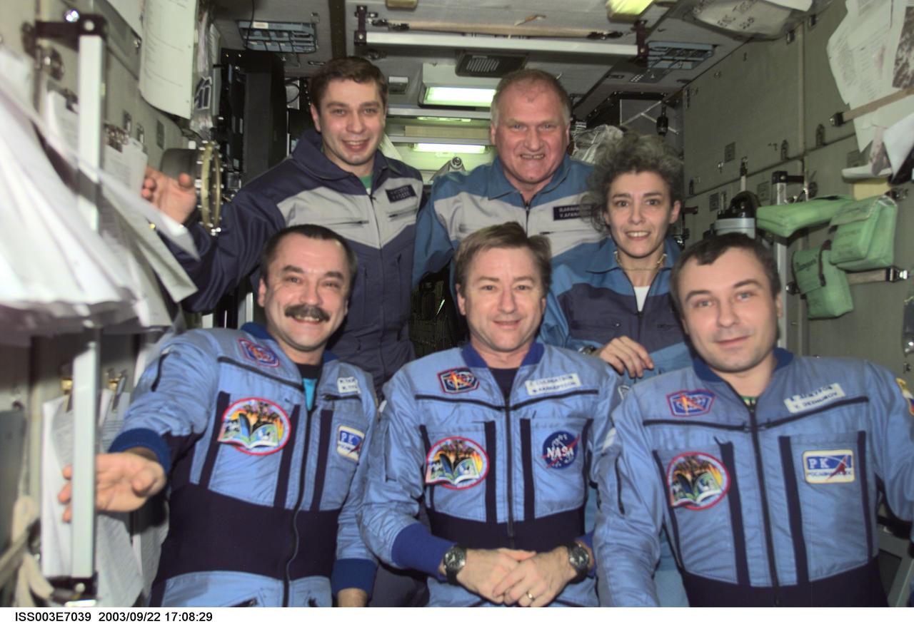 ISS003-E-7039 (23-31 October 2001) --- The Expedition Three crew (bottom) and the Soyuz Taxi crew assemble for a group photo in the Zvezda Service Module on the International Space Station (ISS). The Expedition Three crewmembers are astronaut Frank L. Culbertson, Jr. (center), mission commander, and cosmonauts Mikhail Tyurin (left) and Vladimir N. Dezhurov, both flight engineers. The Soyuz taxi crewmembers are Flight Engineer Konstantin Kozeev (left), Commander Victor Afanasyev, and French Flight Engineer Claudie Haignere. Tyurin, Dezhurov, Afanasyev, and Kozeev represent Rosaviakosmos. Haignere represents ESA, carrying out a flight program for CNES, the French Space Agency, under a commercial contract with the Russian Aviation and Space Agency. This image was taken with a digital still camera.