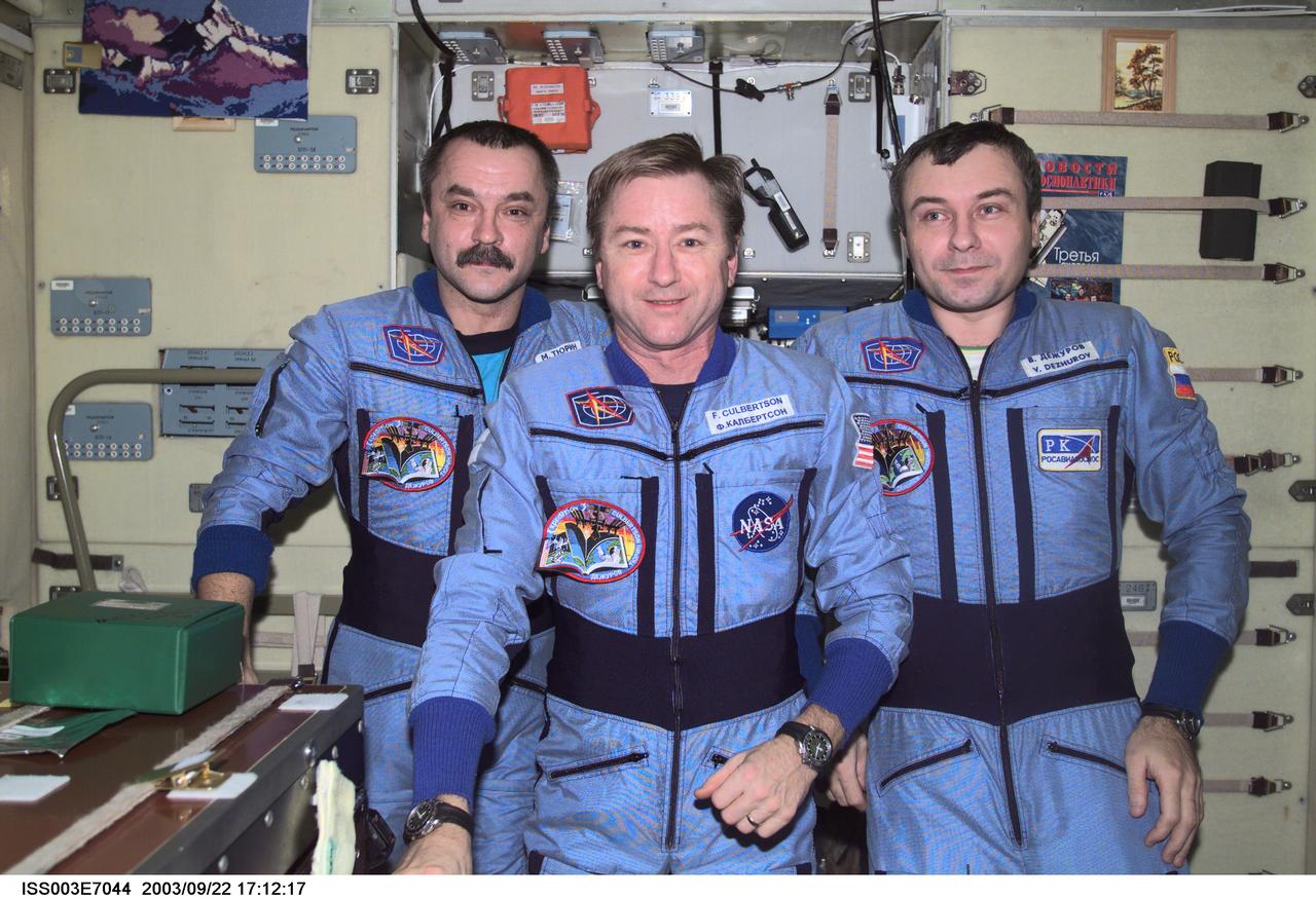 ISS003-E-7044 (October 2001) --- Astronaut Frank L. Culbertson, Jr. (center), Expedition Three mission commander, flanked by cosmonauts Mikhail Tyurin and Vladimir N. Dezhurov, both flight engineers, assemble for a group photo in the Zvezda Service Module on the International Space Station (ISS). Tyurin and Dezhurov represent Rosaviakosmos. This image was taken with a digital still camera.