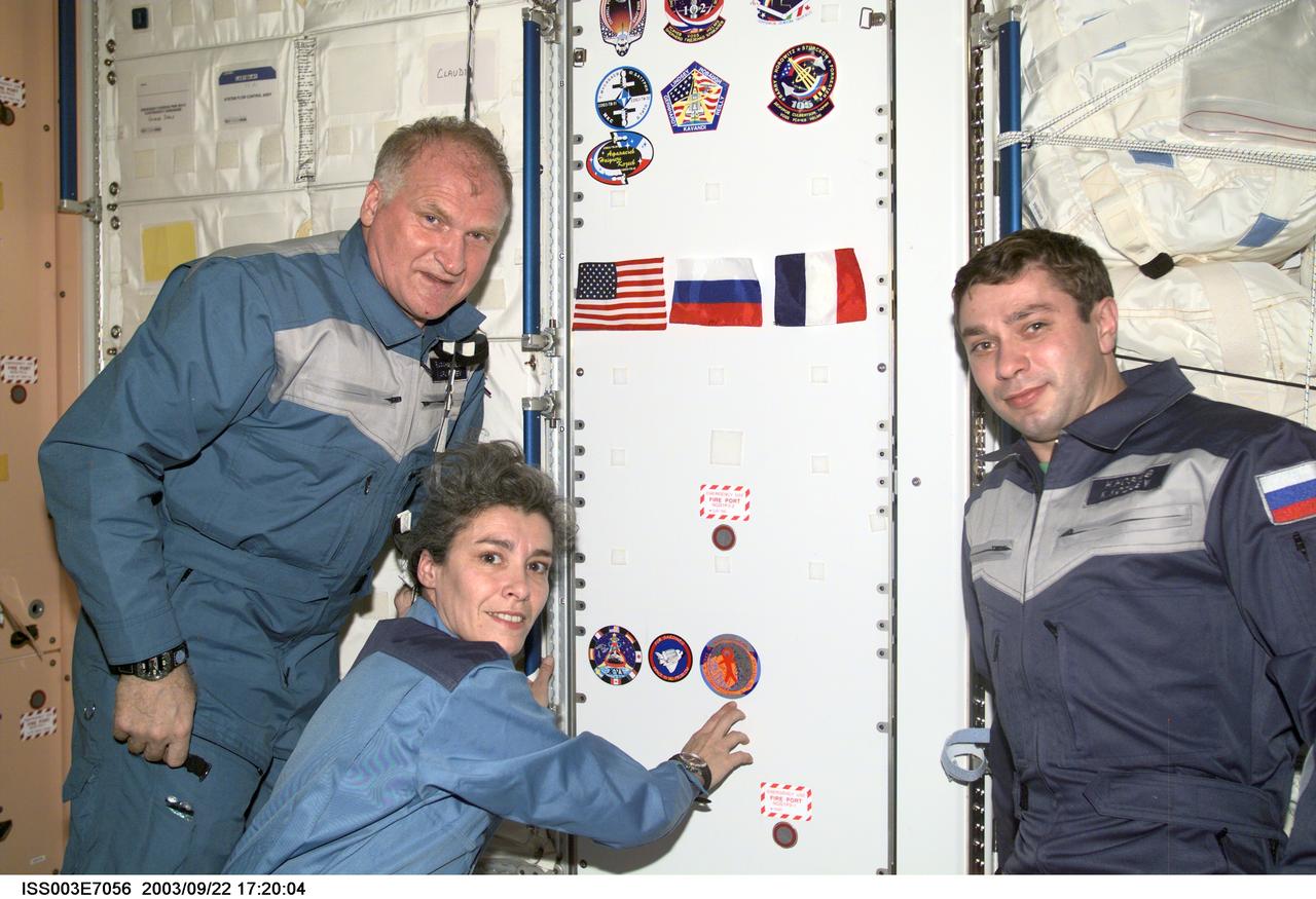ISS003-E-7056 (23-31 October 2001) --- The Soyuz Taxi crewmembers, Commander Victor Afanasyev (left), French Flight Engineer Claudie Haignere and Flight Engineer Konstantin Kozeev, add their crew patch to the growing collection, in the Unity node, of insignias representing crews who have worked on the International Space Station (ISS). Afanasyev and Kozeev represent Rosaviakosmos, and Haignere represents ESA, carrying out a flight program for CNES, the French Space Agency, under a commercial contract with the Russian Aviation and Space Agency. This image was taken with a digital still camera.