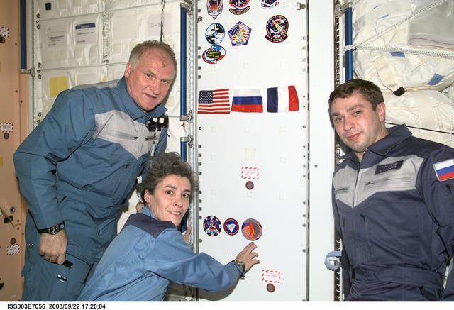 NASA image: The Soyuz Taxi crew adhere their logo to a wall in Node 1 during Expedition Three