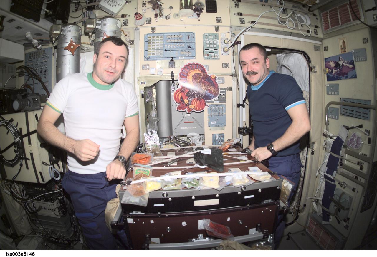 ISS003-E-08146 (22 November 2001) --- Cosmonauts Vladimir N. Dezhurov (left) and Mikhail Tyurin, both Expedition 3 flight engineers representing Rosaviakosmos, eat a Thanksgiving meal in the Zvezda Service Module on the International Space Station (ISS).
