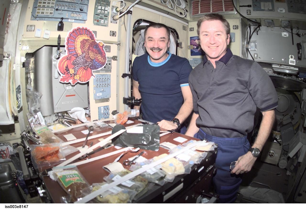 ISS003-E-08147 (22 November 2001) --- Cosmonaut Mikhail Tyurin (left), Expedition 3 flight engineer, and astronaut Frank L. Culbertson, mission commander, eat a Thanksgiving meal in the Zvezda Service Module on the International Space Station (ISS). Tyurin represents Rosaviakosmos.