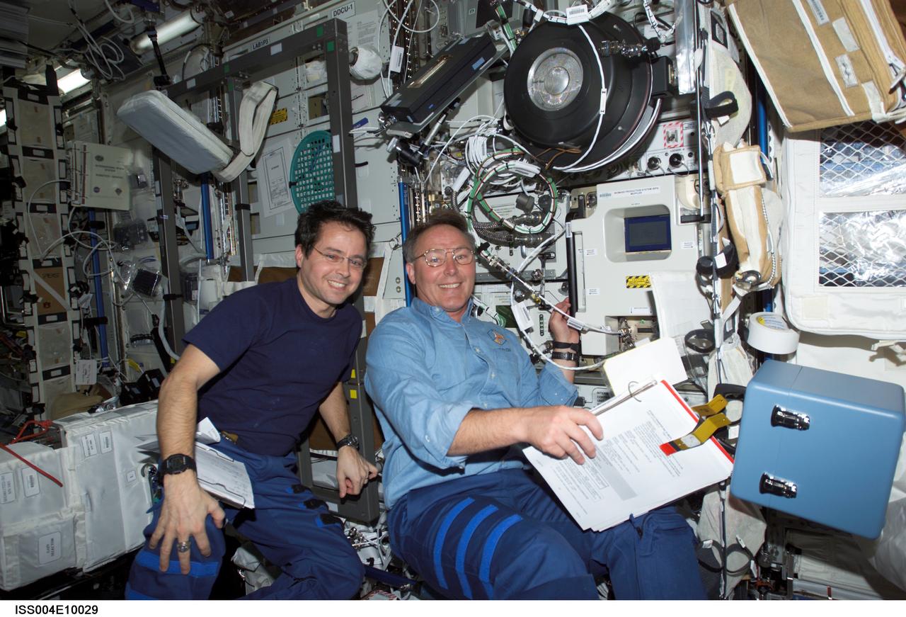 ISS004-E-10029 (12 April 2002) --- Astronauts Daniel W. Bursch (left), Expedition Four flight engineer, and Jerry L. Ross, STS-110 mission specialist, work in the Destiny laboratory on the International Space Station (ISS).