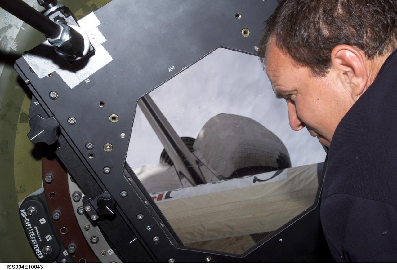 ISS004-E-10043 (15 April 2002) --- Astronaut Michael J. Bloomfield, STS-110 mission commander, looks through the Earth observation window in the Destiny laboratory on the International Space Station (ISS). Portions of the Space Shuttle Atlantis and the Canadarm2 are visible through the window.