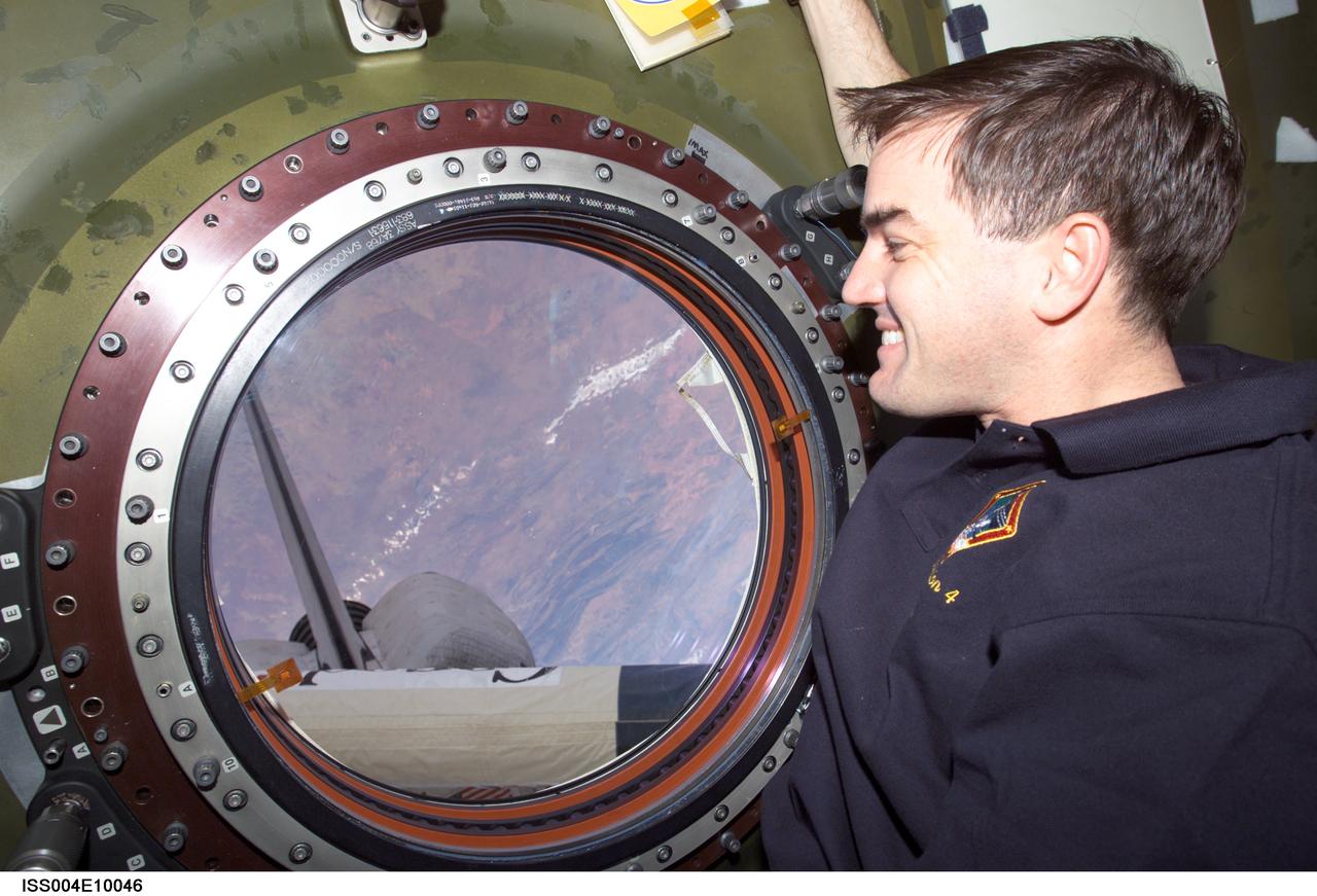 ISS004-E-10046 (16 April 2002) --- Astronaut Rex J. Walheim, STS-110 mission specialist, looks through the Earth observation window in the Destiny laboratory on the International Space Station (ISS). Portions of the Space Shuttle Atlantis and the Canadarm2 are visible through the window.