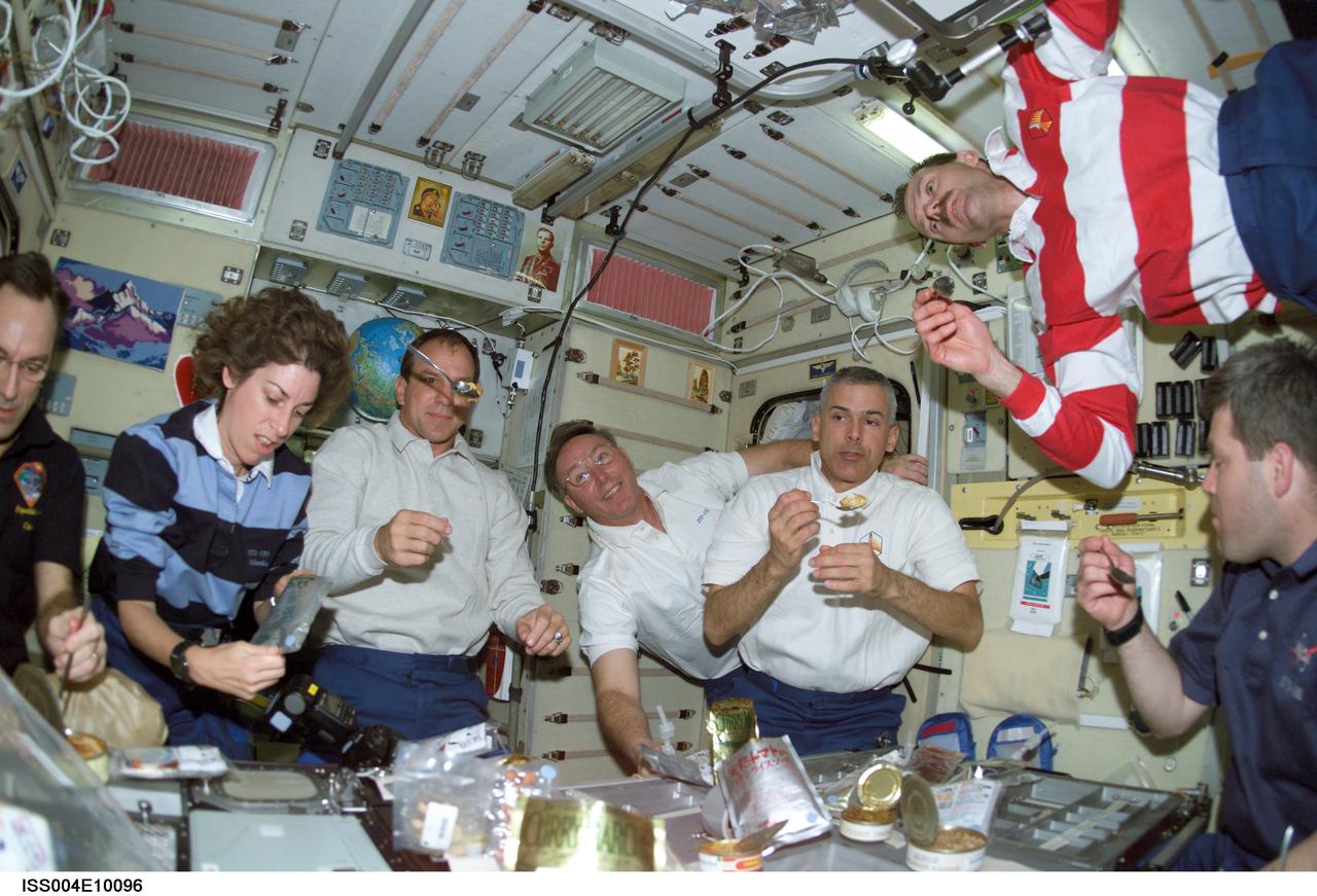 ISS004-E-10096 (16 April 2002) --- The Expedition Four and STS-110 crewmembers share a meal in the Zvezda Service Module on the International Space Station (ISS). From the left are astronauts Carl E. Walz (partially out of frame), Expedition Four flight engineer; Ellen Ochoa, STS-110 mission specialist; Michael J. Bloomfield, STS-110 mission commander; Jerry L. Ross, Lee M. E. Morin, Steven L. Smith, all STS-110 mission specialists; and Stephen N. Frick, STS-110 pilot. The remainders of the crews were out of frame.