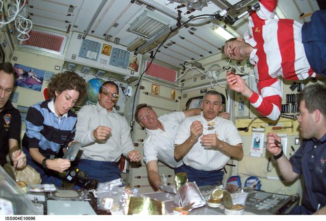 NASA image: STS-110 and Expedition Four crewmembers gather for a meal in the Zvezda SM