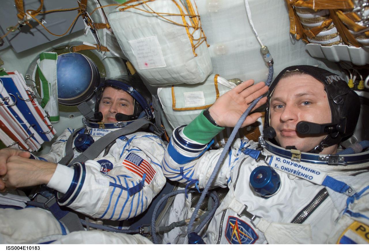 ISS004-E-10183 (20 April 2002) --- Astronaut Daniel W. Bursch (left) and cosmonaut Yury I. Onufrienko, Expedition Four flight engineer and mission commander, respectively, wearing Russian Sokol suits, are seated in the Soyuz 3 spacecraft that is docked to the International Space Station (ISS). The Expedition Four crew undocked the Soyuz 3 capsule from the nadir docking port of the Zarya module of the ISS at 4:16 a.m. (CDT) and flew a short distance down the station for a redocking to the Pirs docking compartment at 4:37 a.m. (CDT) over Central Asia. The move was in preparation for the arrival of the new Soyuz 4 capsule on April 27, 2002, and a three-man “taxi” crew, Commander Yuri Gidzenko, who was a member of the first resident crew of the ISS; Flight Engineer Roberto Vittori of the European Space Agency (ESA); and South African space flight participant Mark Shuttleworth.