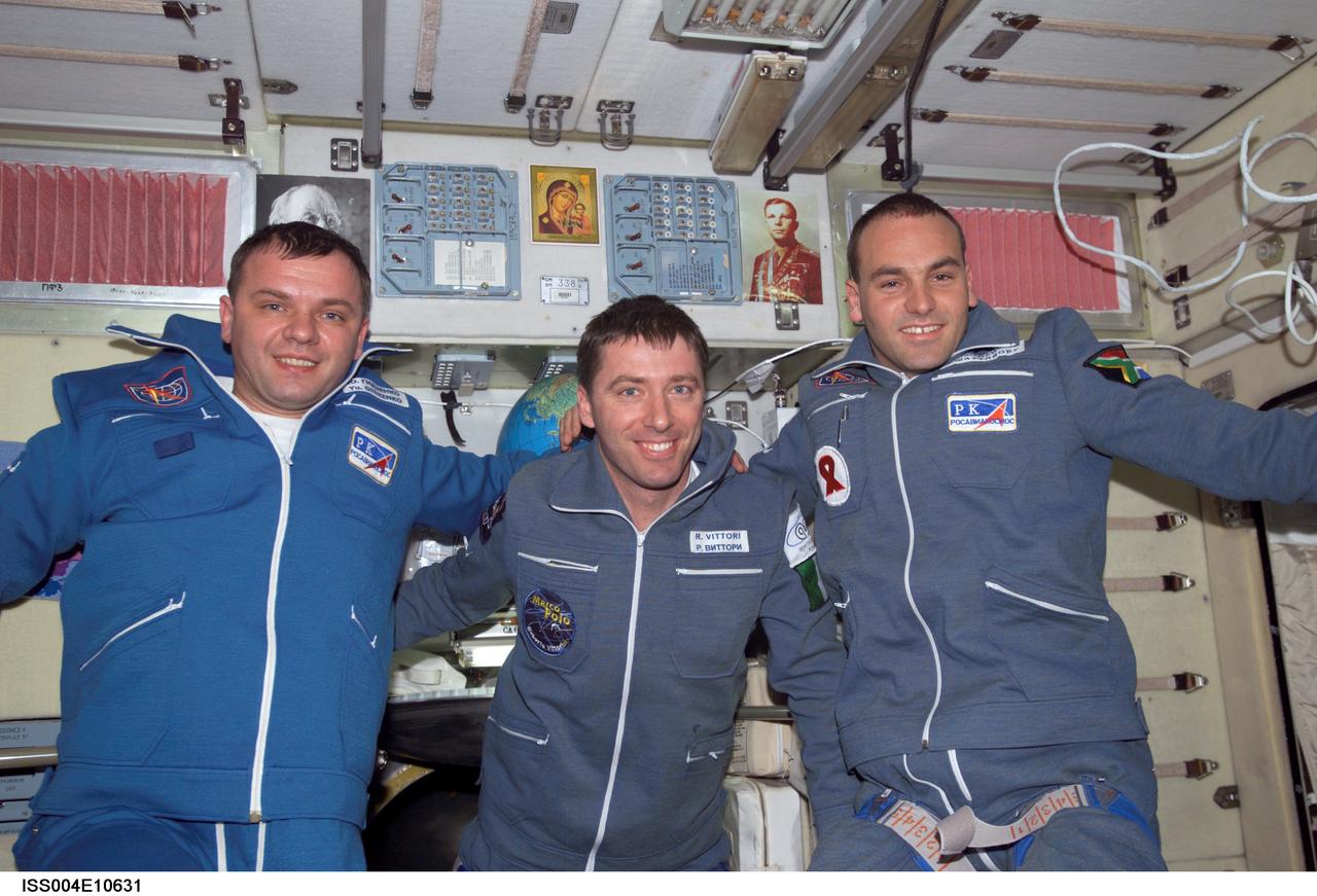 ISS004-E-10631 (27 April 2002) --- The Soyuz Taxi crewmembers pose for a group photo in the Zvezda Service Module on the International Space Station (ISS). From the left are Commander Yuri Gidzenko, who was a member of the first resident crew of the ISS; Flight Engineer Roberto Vittori of the European Space Agency (ESA); and South African space flight participant Mark Shuttleworth. The &#0147;taxi&#0148; crew arrived at the orbital outpost on April 27, 2002 at 2:56 a.m. (CDT) as the two vehicles flew over Central Asia. Gidzenko represents Rosaviakosmos.