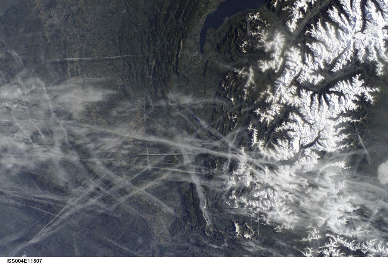 ISS004-E-11807 (15 May 2002) --- This digital photograph, taken through the windows of the International Space Station on May 15, 2002, shows condensation trails over the Rhône Valley in the region west of Lyon, France. Condensation trails-or contrails-are straight lines of ice crystals that form in the wake of jet liners where air temperatures are lower than about -40 degrees Centigrade. Scientists have observed that newer contrails are thin whereas older trails have widened with time as a result of light winds. Because of this tendency for thin contrails to cover greater areas with time, it is estimated that these “artificial clouds” cover 0.1 per cent of the planet’s surface. Percentages are far higher in some places, say the scientists, such as southern California, the Ohio River Valley and parts of Europe, as illustrated here. The climatic impact of such clouds is poorly understood, which is why scientists continue to study them using images such as this.
