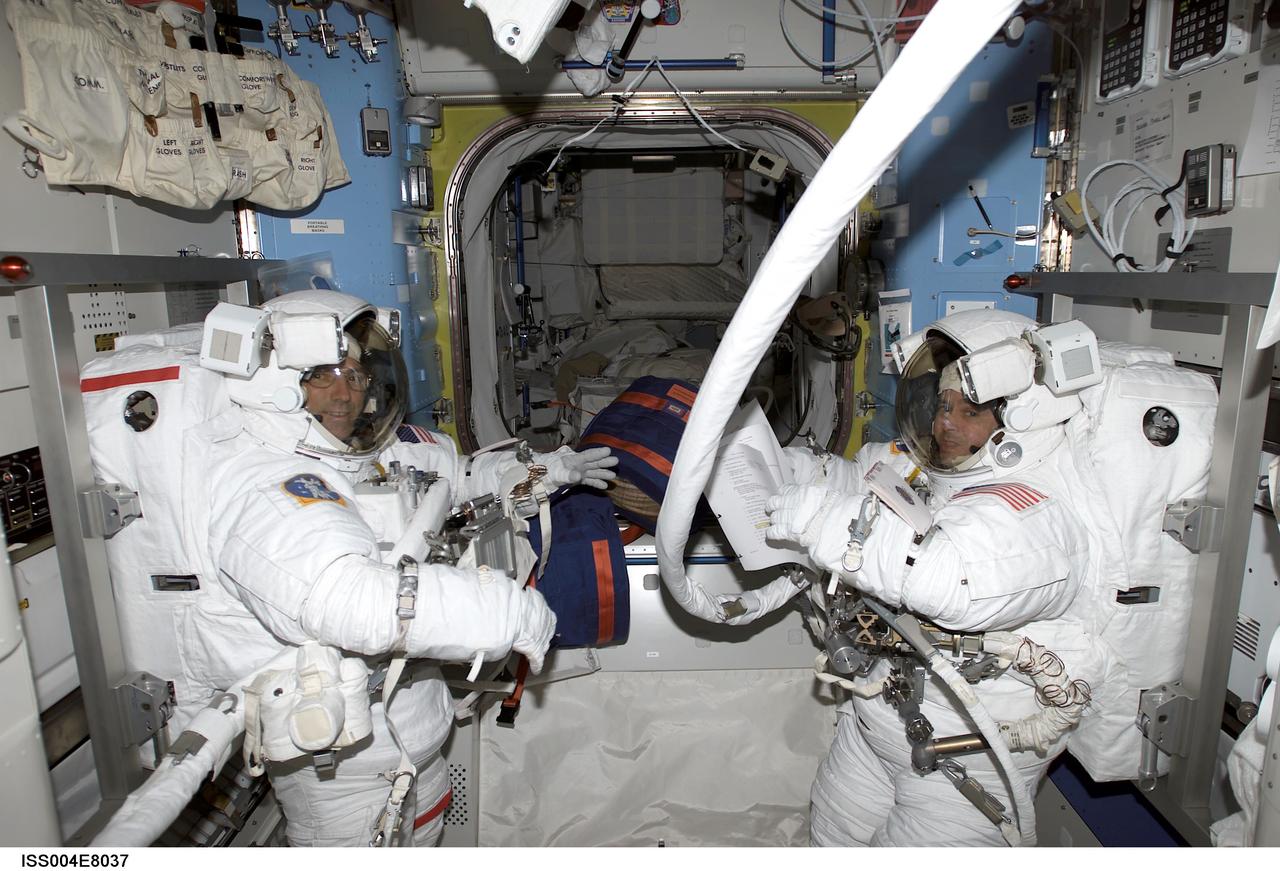 ISS004-E-8037 (20 February 2002) --- Astronauts Carl E. Walz (left) and Daniel W. Bursch, Expedition Four flight engineers, undergo a pressure check in Quest's Equipment Lock,  prior to the  beginning of what turned out to be a five-hour, 47-minute session of extravehicular activity (EVA). The image was recorded with a digital still camera.