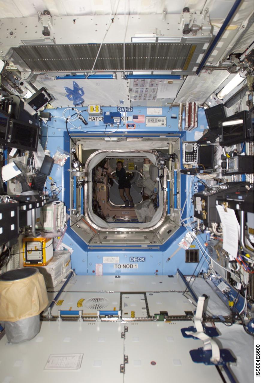 ISS004-E-8600 (14 March 2002) --- The interior of the Destiny laboratory on the International Space Station (ISS) is photographed by an Expedition Four crewmember. Cosmonaut Yury I. Onufrienko, Expedition Four mission commander representing Rosaviakosmos, is visible in the Unity node of the orbital outpost. The image was taken with a digital still camera.
