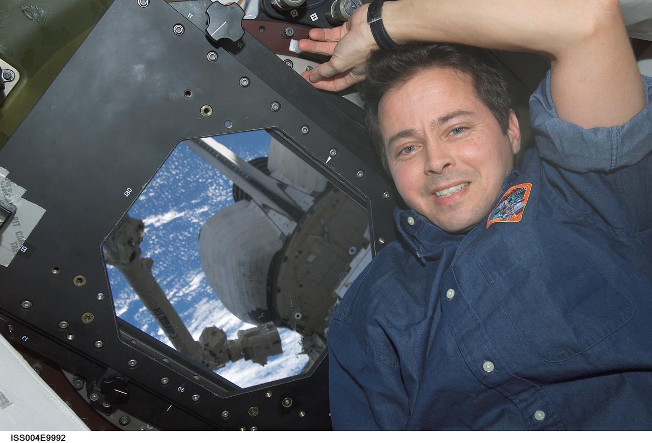 ISS004-E-9992 (10 April 2002) --- Astronaut Daniel W. Bursch, Expedition Four flight engineer, is photographed near a Destiny laboratory window on the International Space Station (ISS). Portions of the Space Shuttle Atlantis and the Canadarm2 are visible through the window.