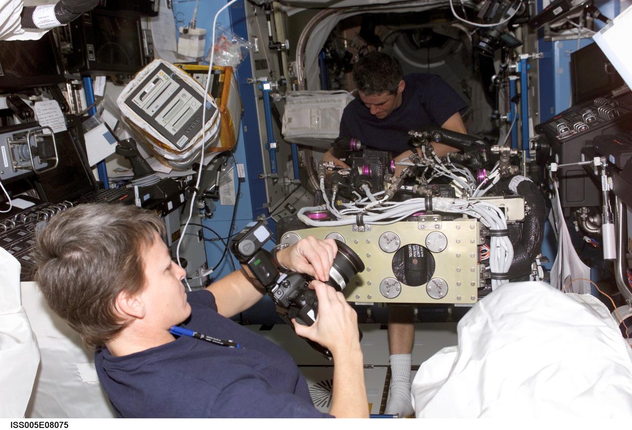 ISS005-E-08075 (July 2002) --- Astronaut Peggy A. Whitson (foreground), Expedition Five flight engineer, prepares to use a still camera in the Destiny laboratory on the International Space Station (ISS). Cosmonaut Valery G. Korzun, mission commander, is visible in the background as he works on equipment. Korzun represents Rosaviakosmos.